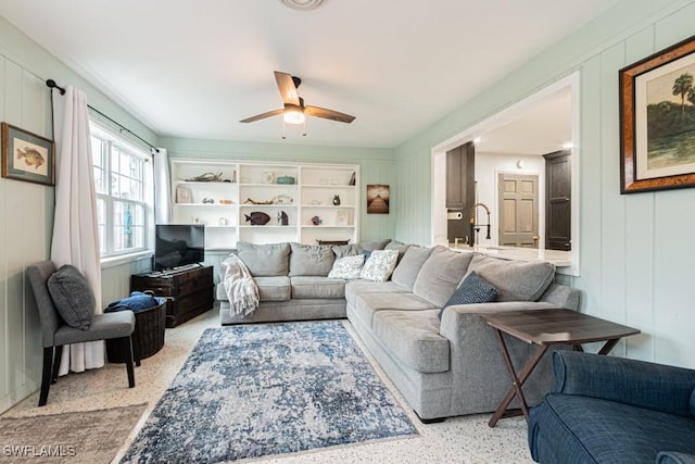 living area with ceiling fan and light speckled floor