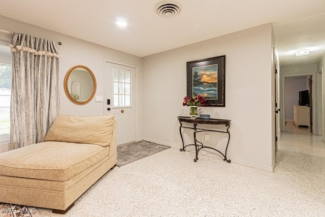 sitting room featuring visible vents, baseboards, and speckled floor