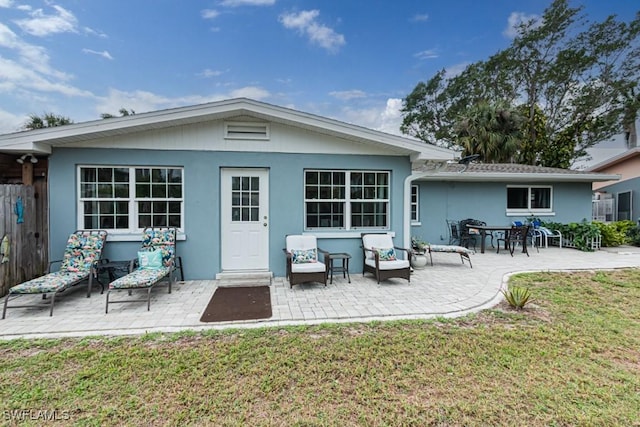 back of property featuring a patio, a yard, and stucco siding