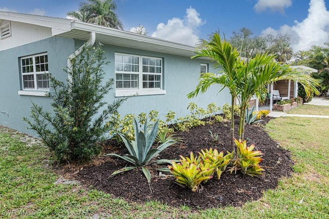 view of side of property with a lawn and stucco siding