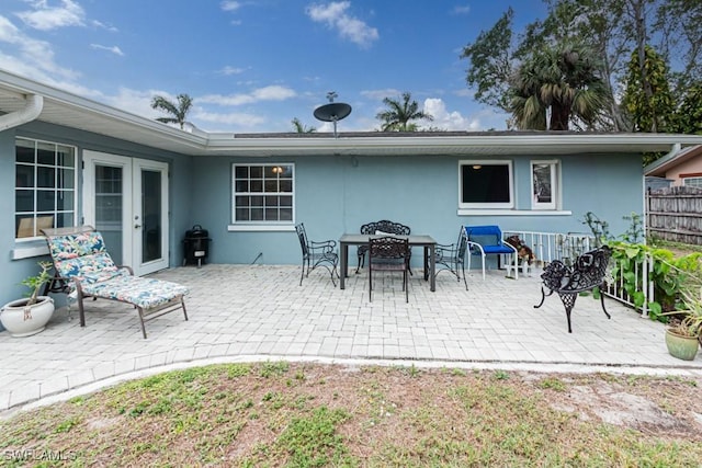 view of patio with french doors, fence, and outdoor dining area