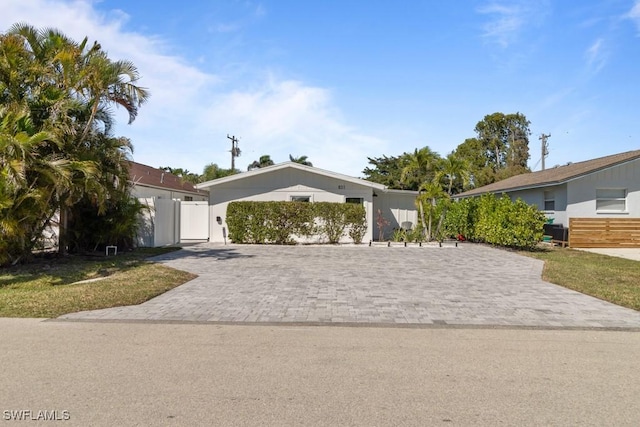 view of front of house with decorative driveway and fence