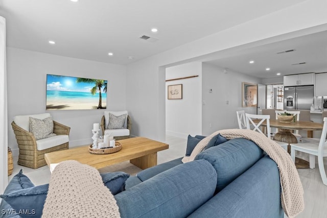 living area with recessed lighting, visible vents, and baseboards