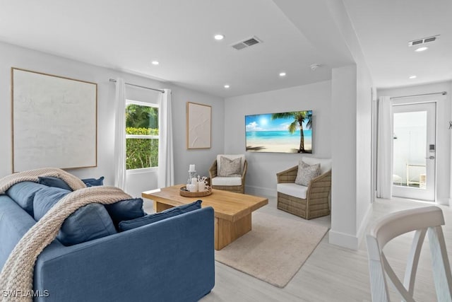 living room with light wood-type flooring, visible vents, and recessed lighting