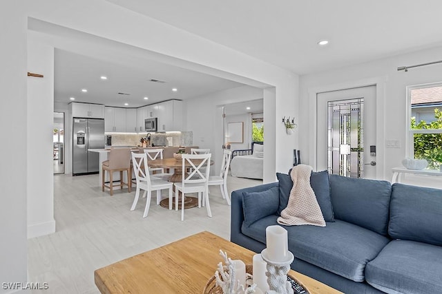 living room featuring baseboards, light wood finished floors, visible vents, and recessed lighting