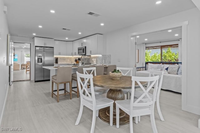 dining space with light wood-style floors, recessed lighting, and visible vents