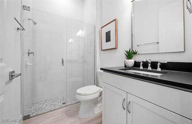 full bathroom featuring wood finished floors, a stall shower, vanity, and toilet