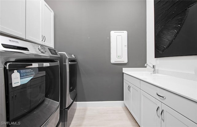 laundry area with baseboards, a sink, cabinet space, and washer and dryer