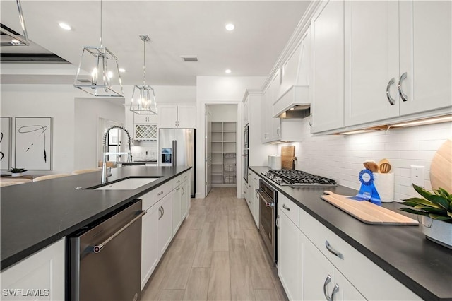 kitchen with dark countertops, decorative backsplash, appliances with stainless steel finishes, white cabinets, and a sink