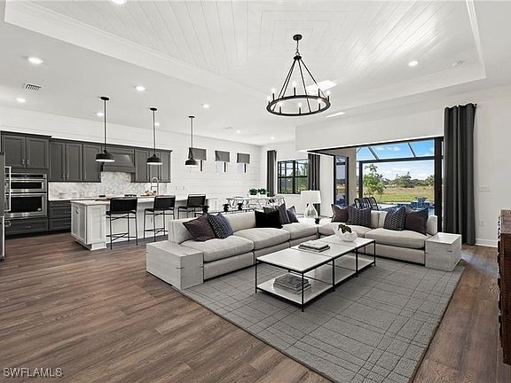 living area featuring visible vents, a chandelier, dark wood-type flooring, and a raised ceiling