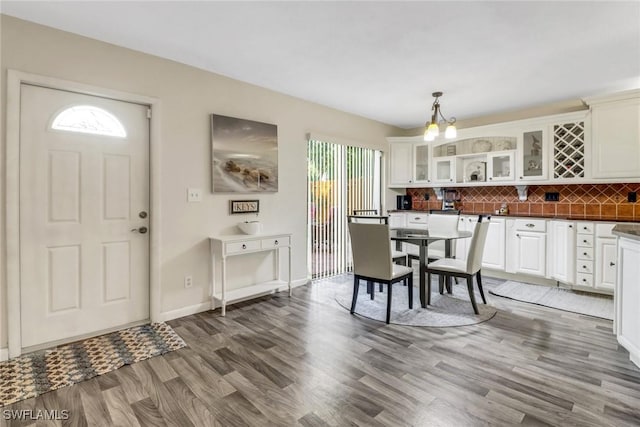 dining room with a notable chandelier, baseboards, and wood finished floors