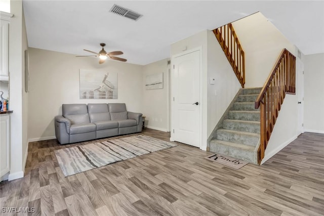 living room featuring stairs, visible vents, and wood finished floors