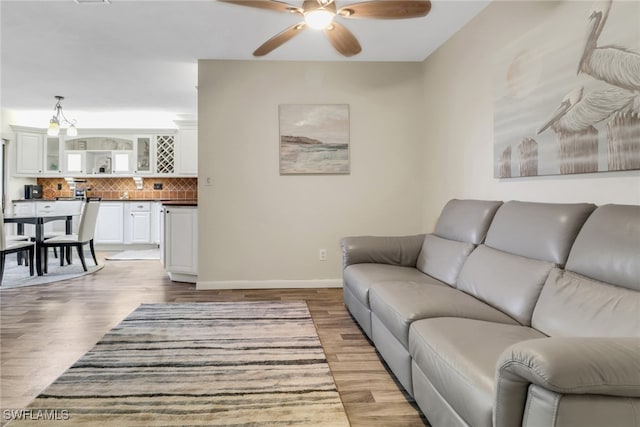 living area with ceiling fan, wood finished floors, and baseboards