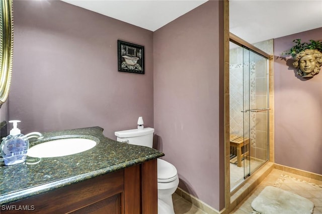 bathroom featuring a stall shower, baseboards, vanity, and toilet