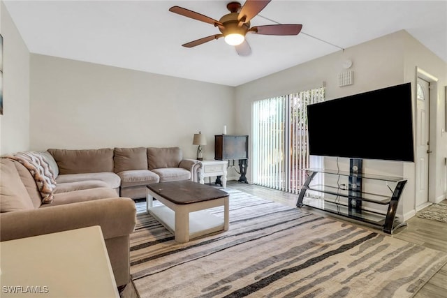 living room featuring ceiling fan, baseboards, and wood finished floors