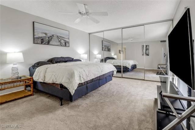 carpeted bedroom with a textured ceiling, a closet, and a ceiling fan