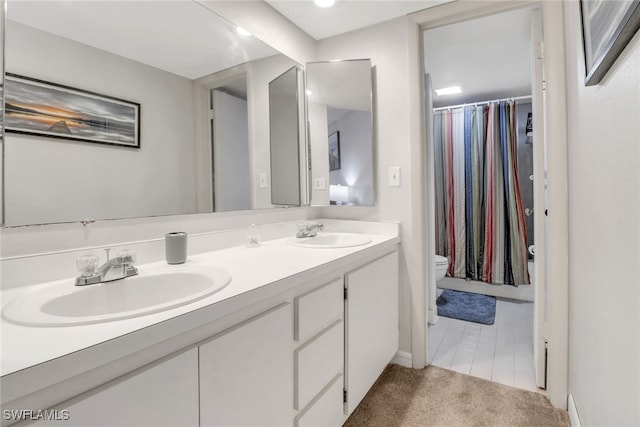 full bathroom featuring double vanity, a sink, and toilet