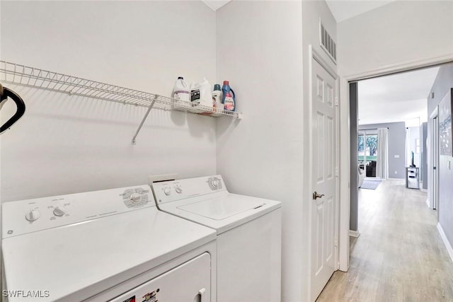 laundry area with laundry area, baseboards, visible vents, washing machine and clothes dryer, and light wood-style floors