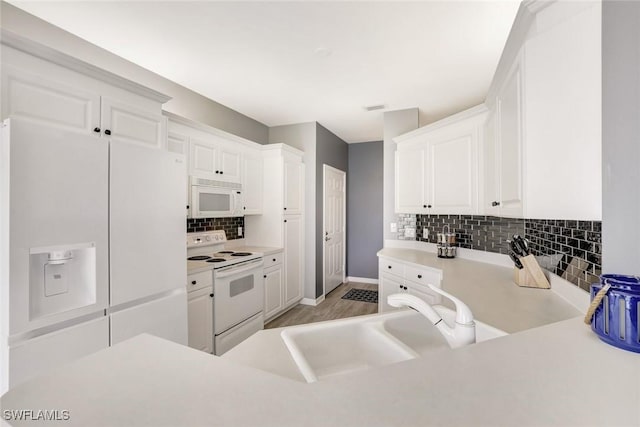 kitchen with tasteful backsplash, light countertops, white cabinets, a sink, and white appliances