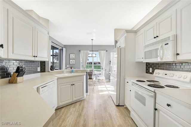 kitchen featuring light countertops, light wood-style flooring, white cabinets, a sink, and white appliances