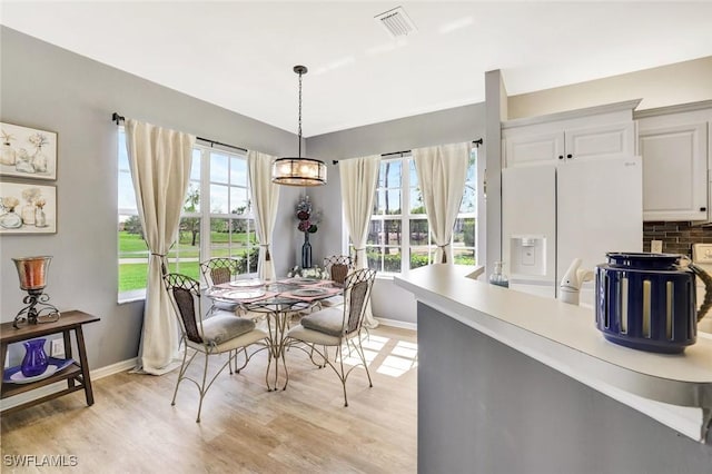 dining area featuring light wood finished floors, baseboards, and visible vents