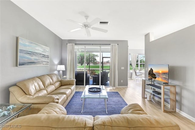 living room with light wood finished floors, baseboards, visible vents, and ceiling fan