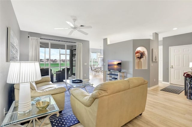 living area with a ceiling fan, baseboards, and light wood finished floors