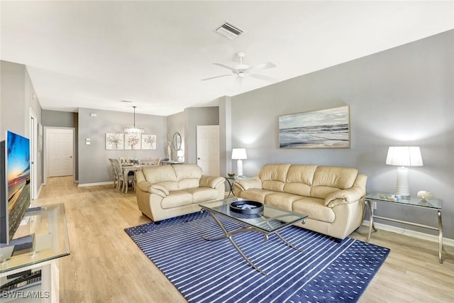 living room featuring light wood-type flooring, baseboards, visible vents, and a ceiling fan