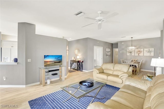 living area with ceiling fan, wood finished floors, visible vents, and baseboards