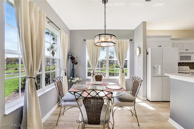 dining space with a chandelier, plenty of natural light, light wood-style flooring, and baseboards