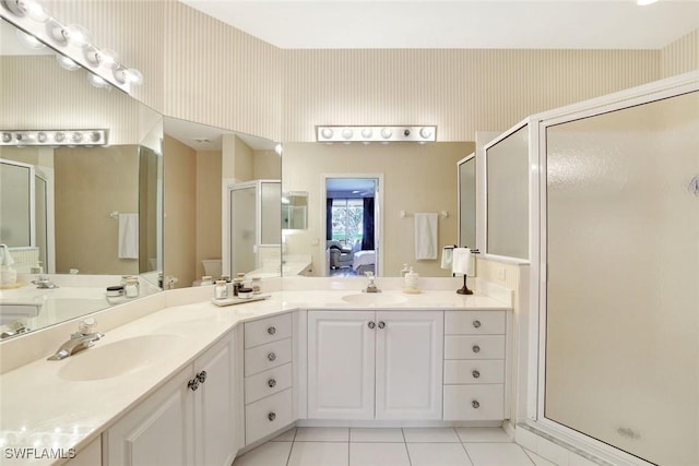 ensuite bathroom featuring a stall shower, double vanity, a sink, and wallpapered walls