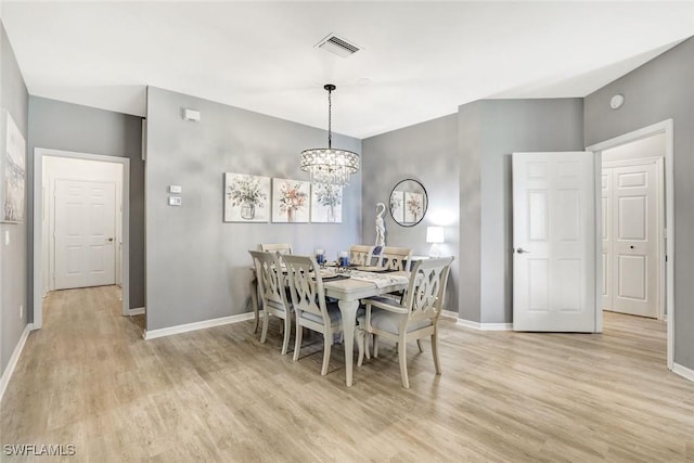 dining room with an inviting chandelier, light wood-type flooring, visible vents, and baseboards