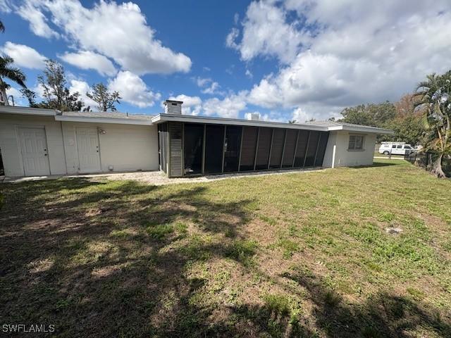 back of house featuring a sunroom and a lawn