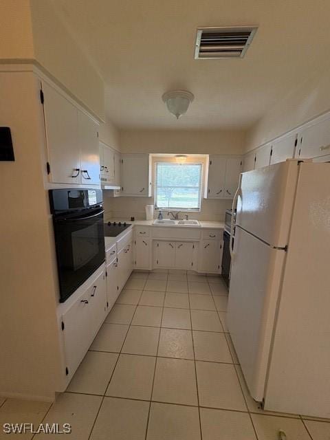 kitchen featuring black appliances, white cabinetry, visible vents, and a sink