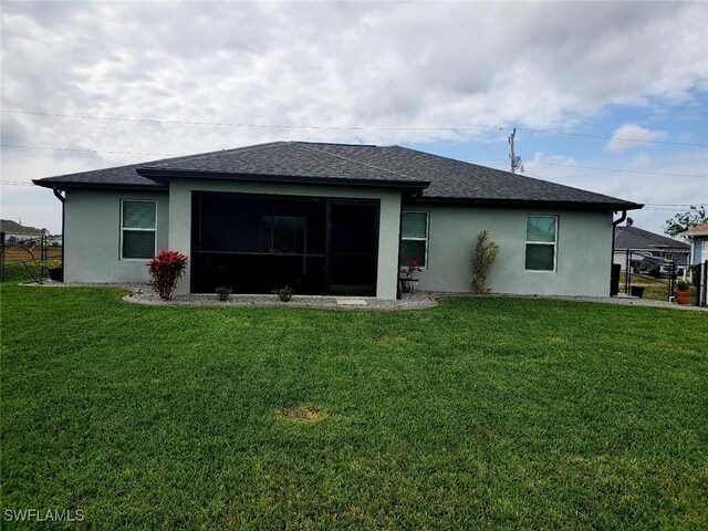 back of property featuring a shingled roof, a lawn, and stucco siding