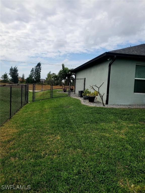 view of yard featuring fence, a gate, and central air condition unit