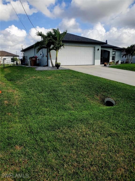 single story home with an attached garage, driveway, a front yard, and stucco siding