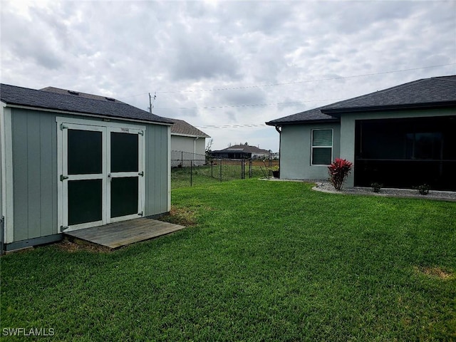 view of yard featuring an outbuilding, a storage shed, and fence