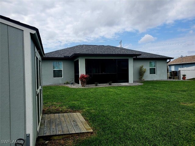 rear view of house with roof with shingles, a lawn, and stucco siding