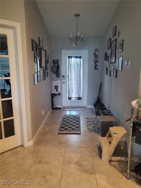 doorway featuring baseboards, vaulted ceiling, a notable chandelier, and tile patterned floors