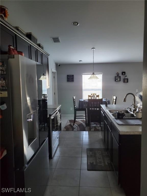 kitchen with visible vents, tile patterned flooring, stainless steel appliances, pendant lighting, and a sink