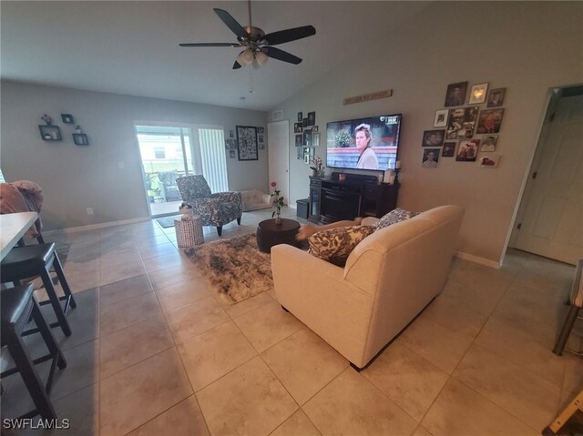 living area featuring lofted ceiling, ceiling fan, light tile patterned flooring, and baseboards