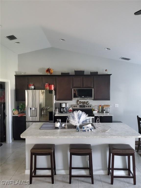 kitchen featuring appliances with stainless steel finishes, a breakfast bar, visible vents, and lofted ceiling