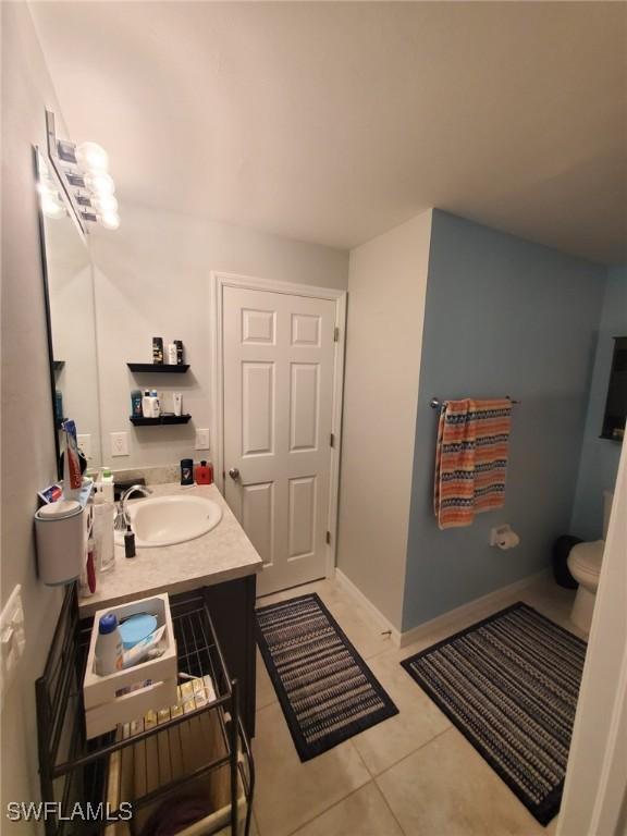 bathroom with toilet, tile patterned flooring, vanity, and baseboards