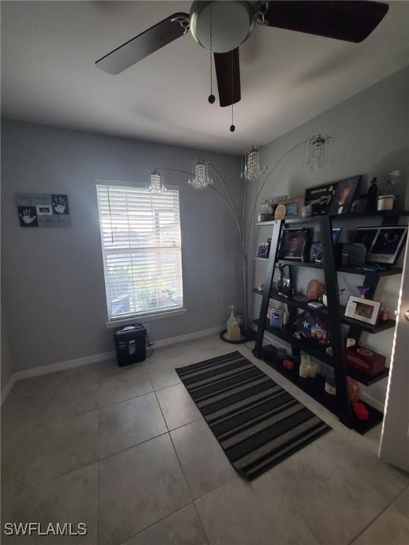 workout area featuring tile patterned flooring, a ceiling fan, and baseboards