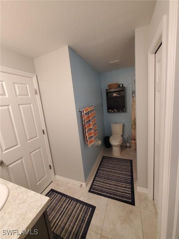 full bathroom with baseboards, vanity, toilet, and tile patterned floors