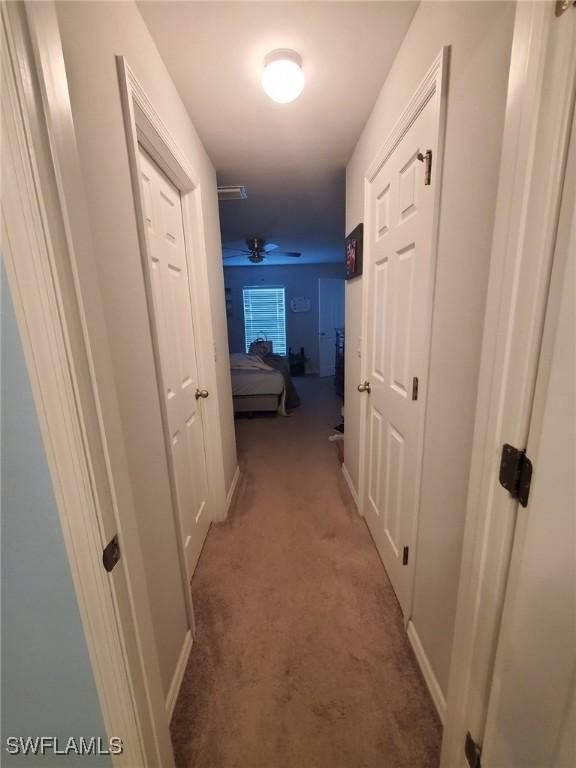 corridor featuring light carpet, visible vents, and baseboards