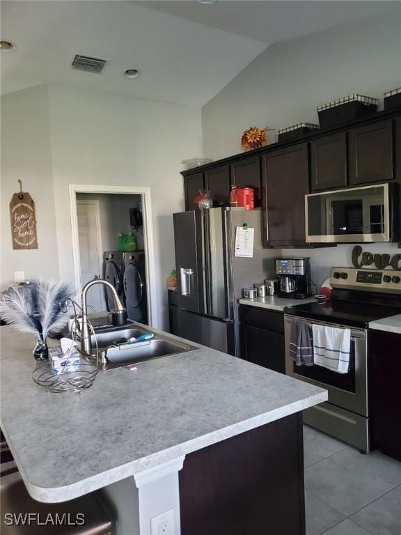 kitchen featuring light countertops, visible vents, appliances with stainless steel finishes, washing machine and dryer, and a sink