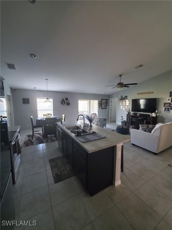 kitchen featuring visible vents, a sink, an island with sink, and light tile patterned floors