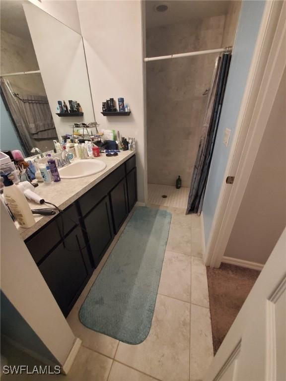 bathroom featuring a tile shower, vanity, and tile patterned floors